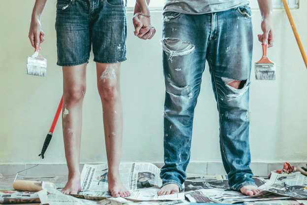 couple holding hands after painting a wall