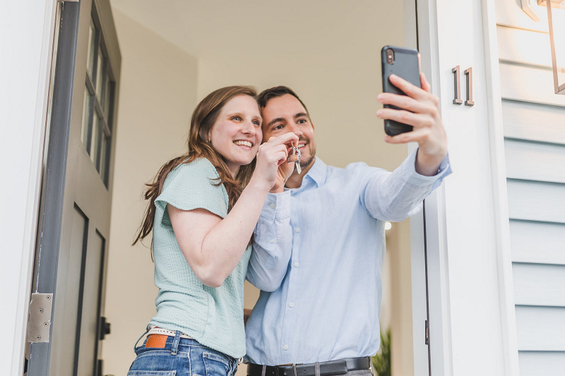young couple taking selfie after purchasing a home
