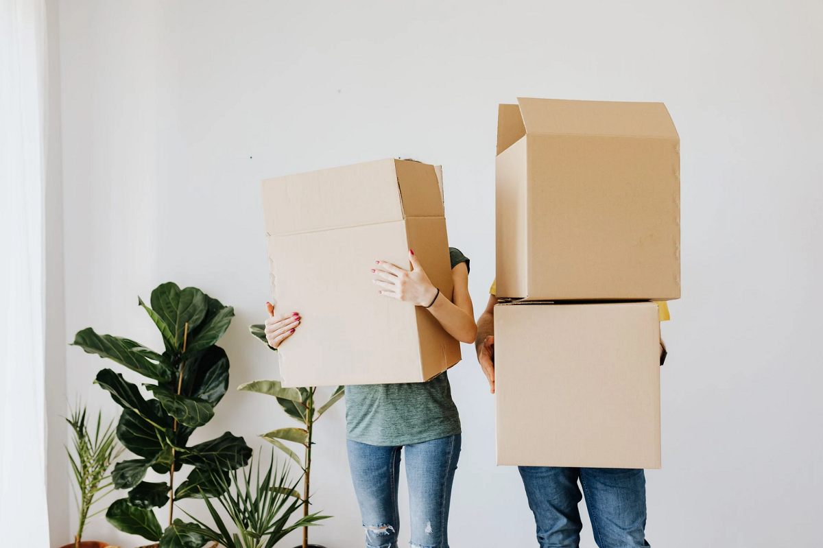 young couple moving into a new home with heavy boxes