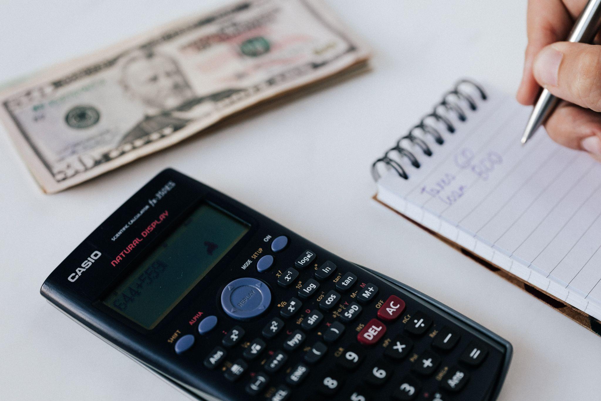 male writing down expenses with a calculator