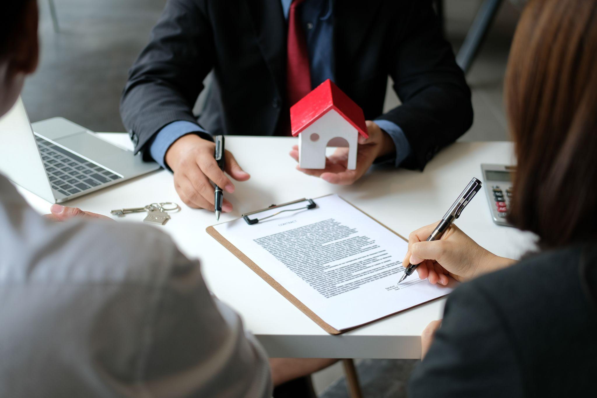 couple signing a mortgage contract agreement with realtor