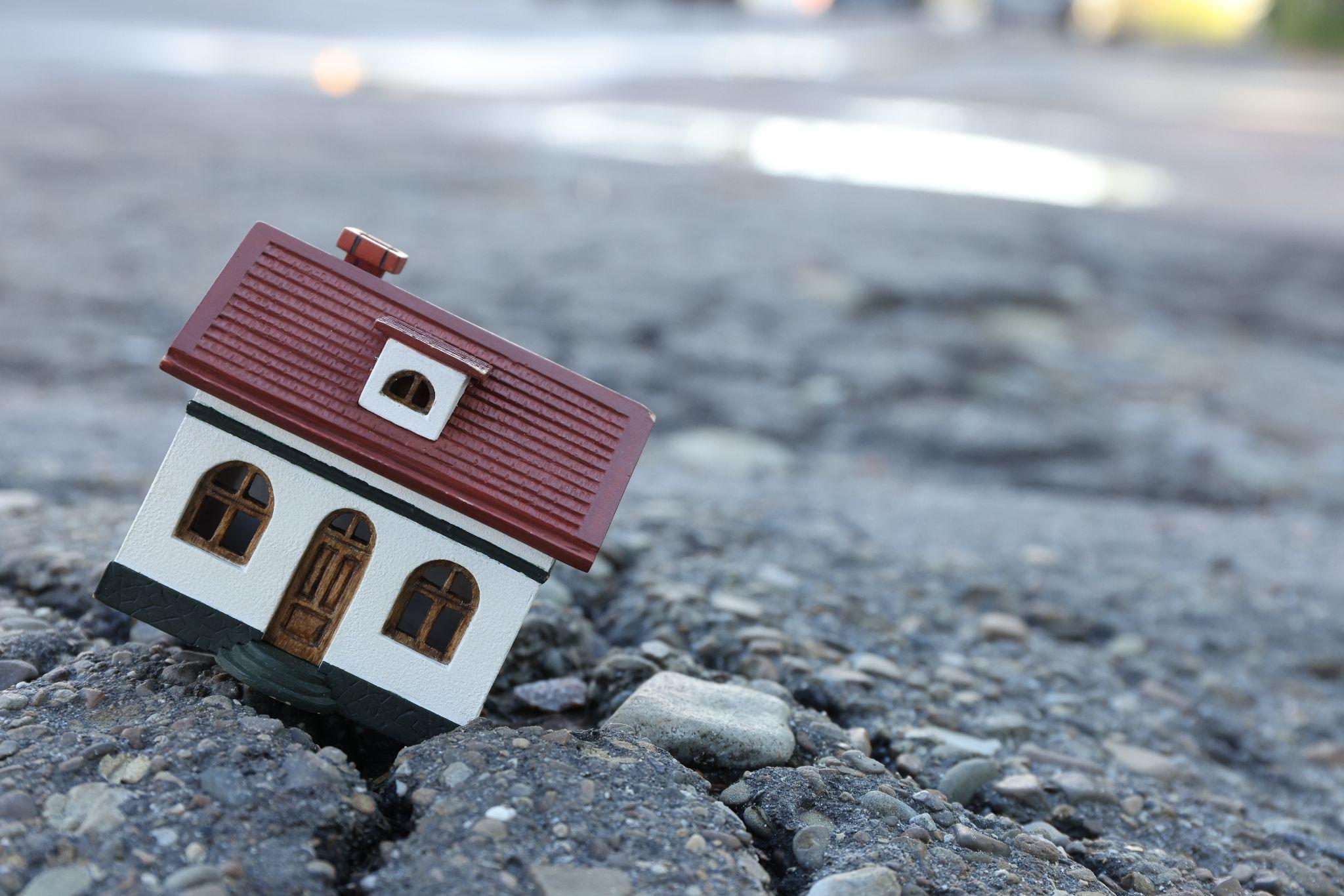 House miniature in a pavement crack: a representation of a house with foundation problems