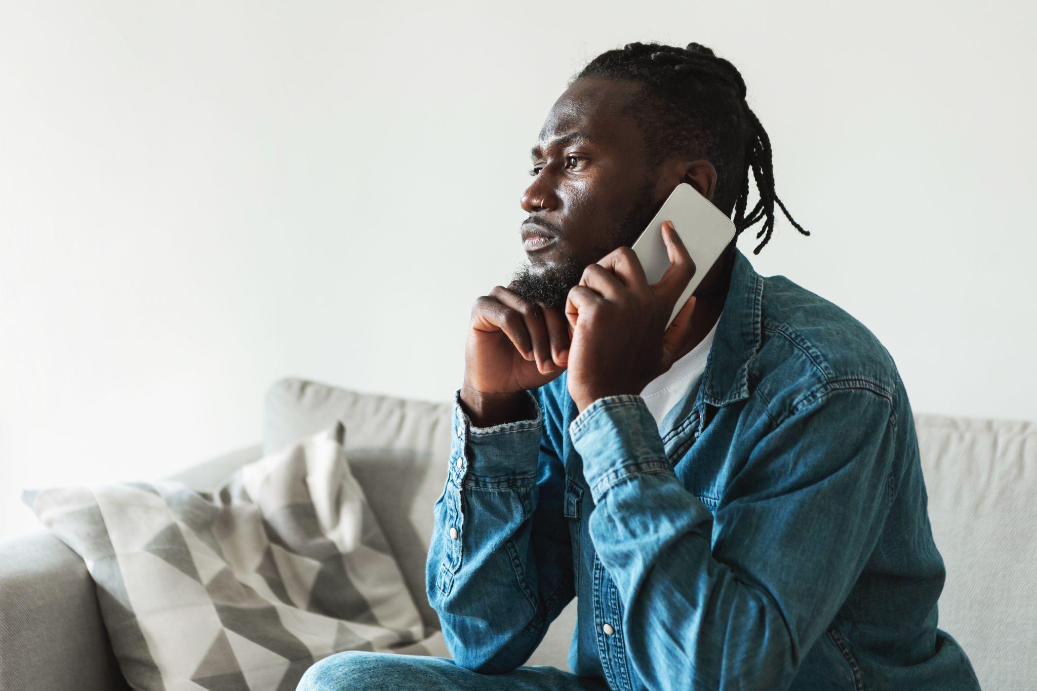 Man on the phone learning that his home sale has fallen through looking disappointed