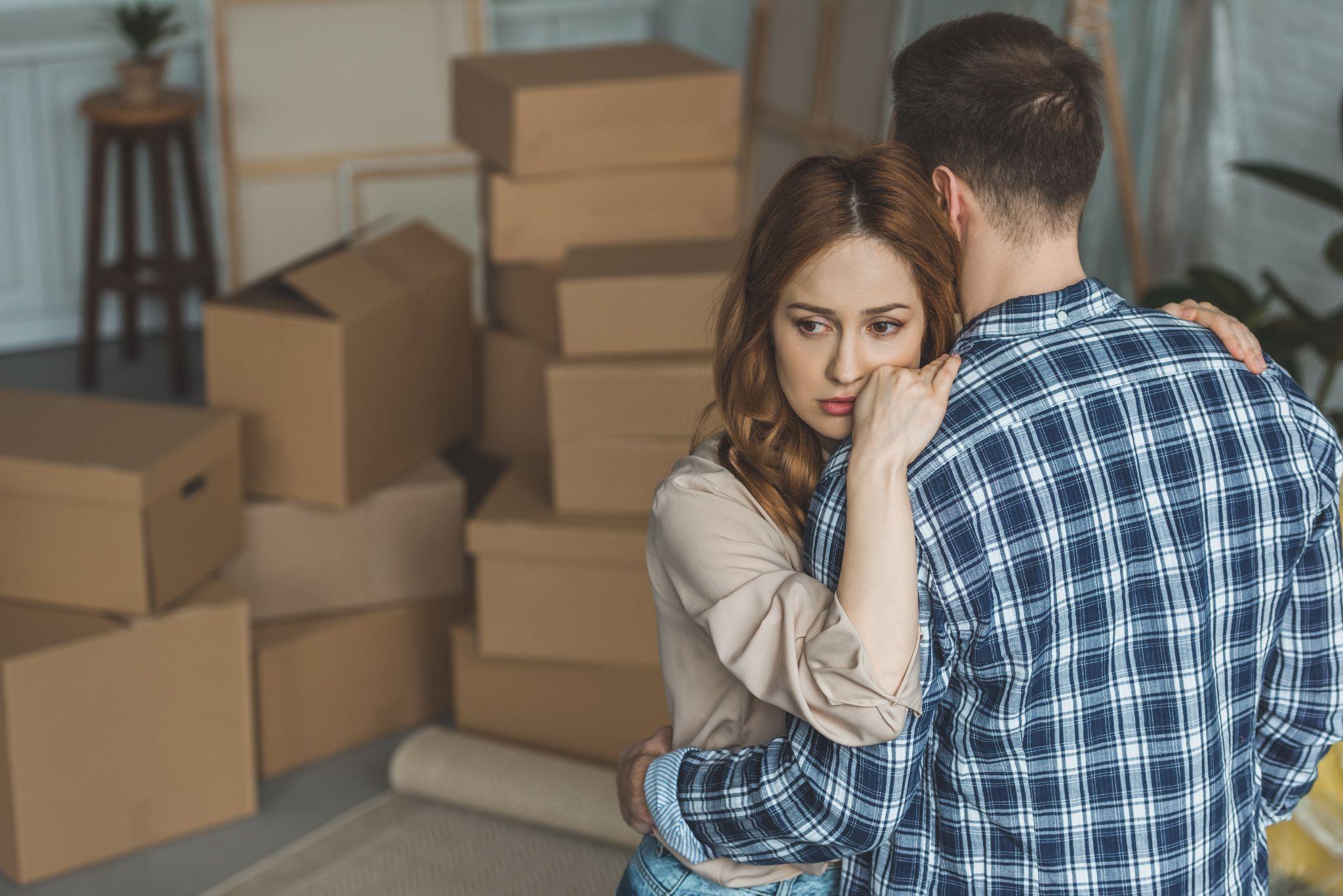 An emotionally distraught woman with moving boxes behind her