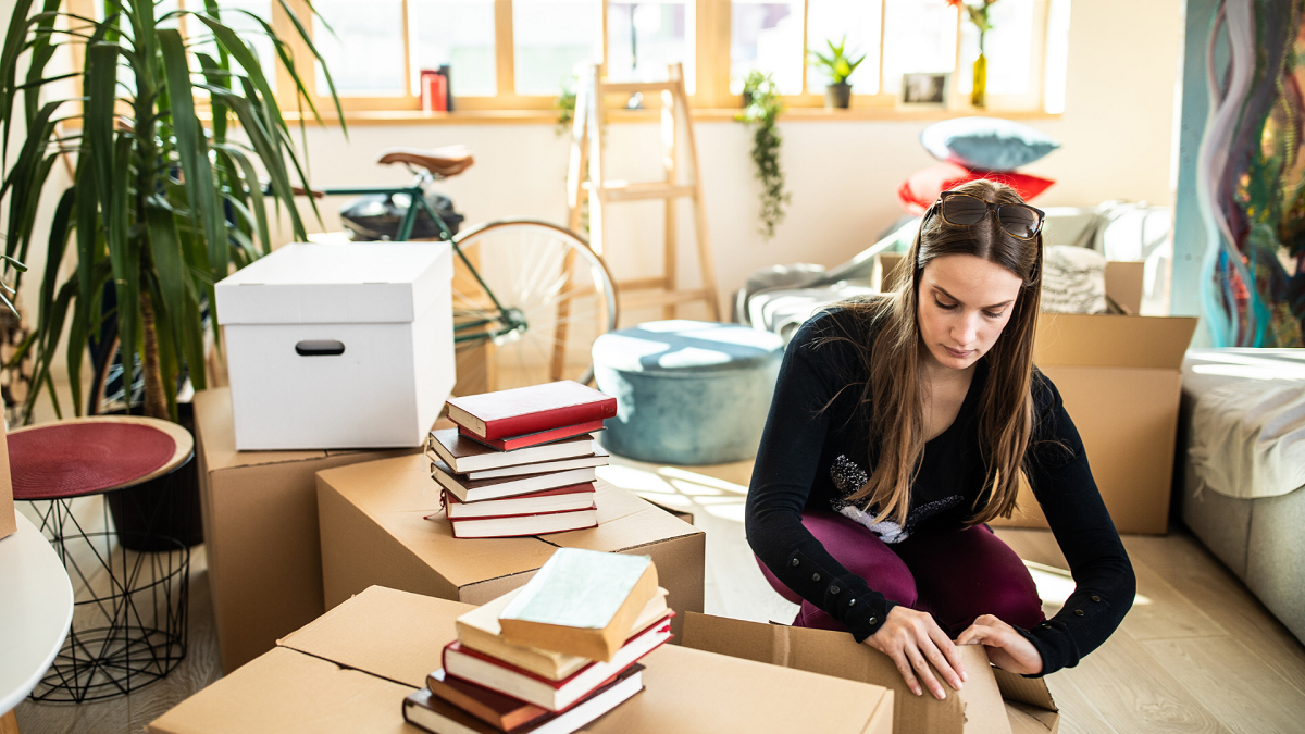 Cheerful attractive woman packing cardboard boxes during moving house