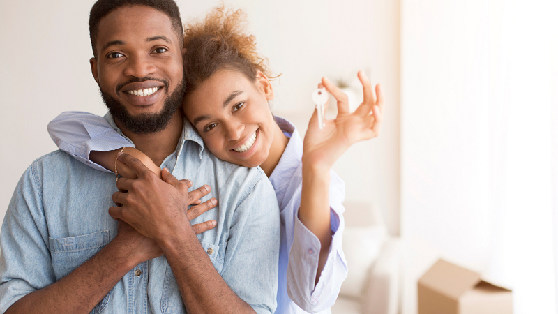 Couple holding new home key hugging standing in own house