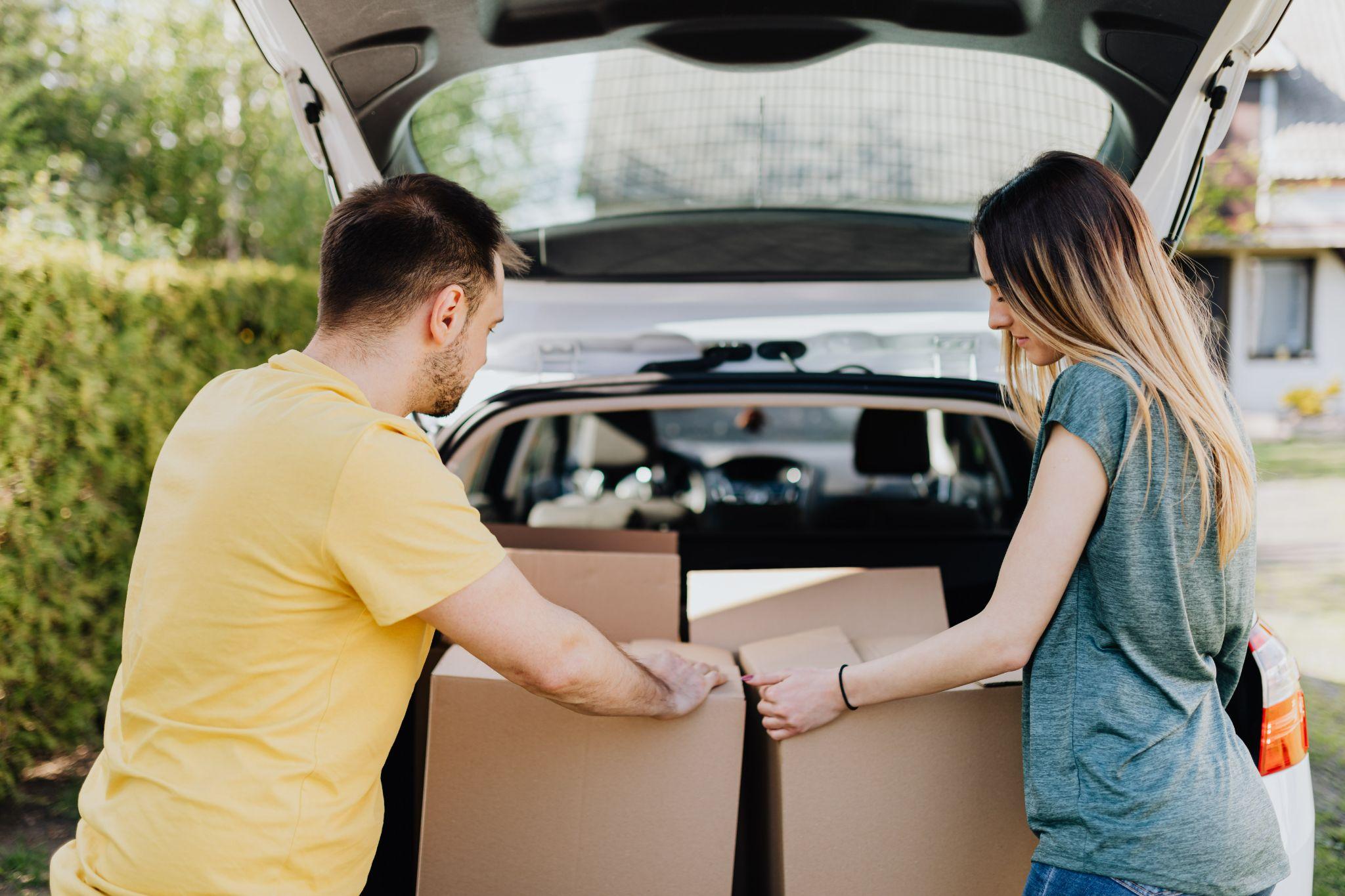 couple putting carton boxes in car trunk