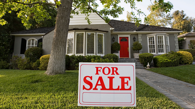 grey house with red for sale sign in front yard