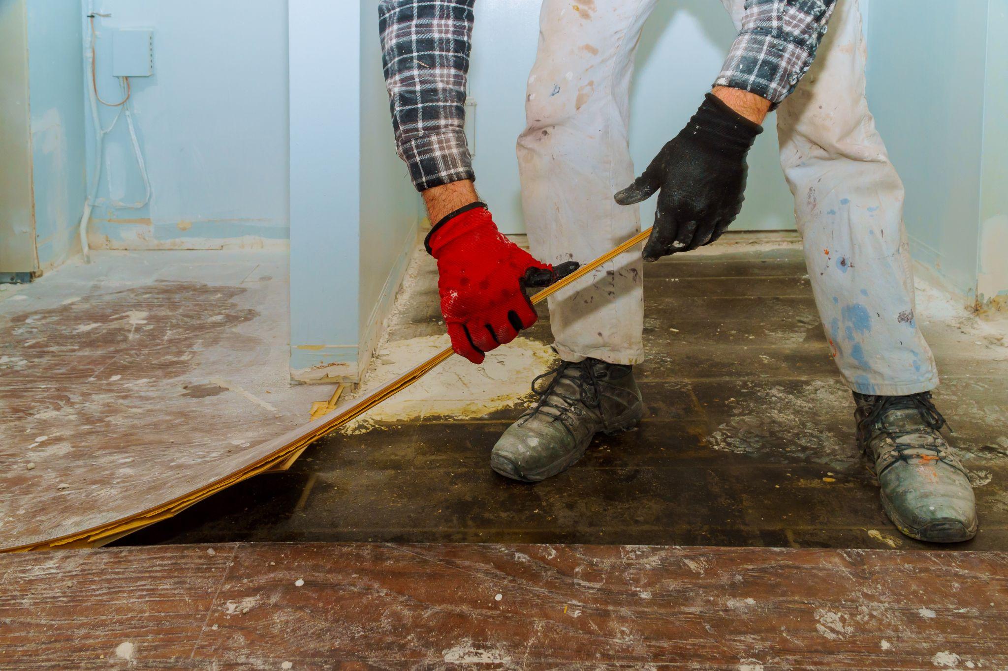 Handyman removing old laminated parquet flooring