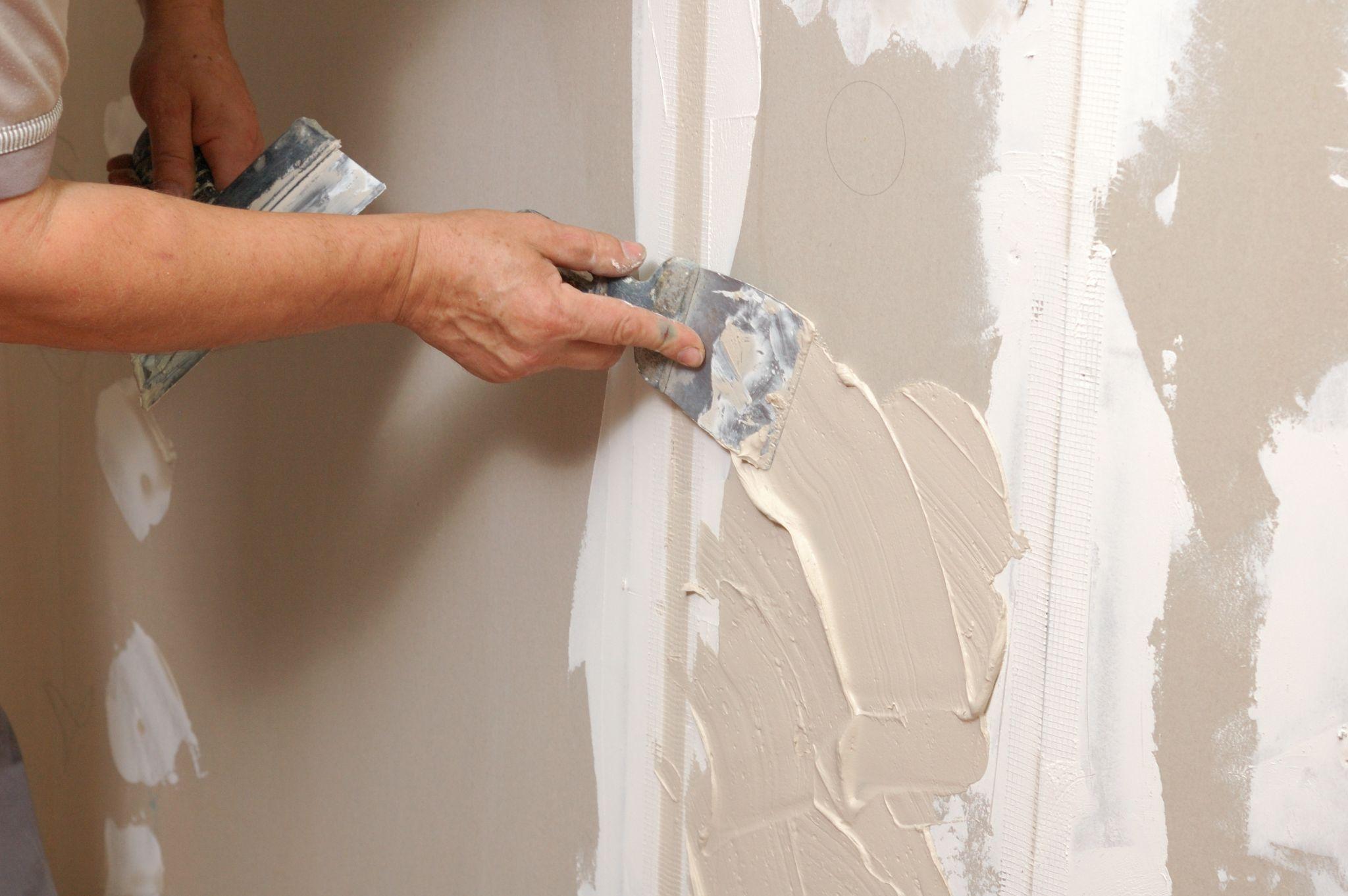 Hispanic painter preparing the surface of a wall before painting.