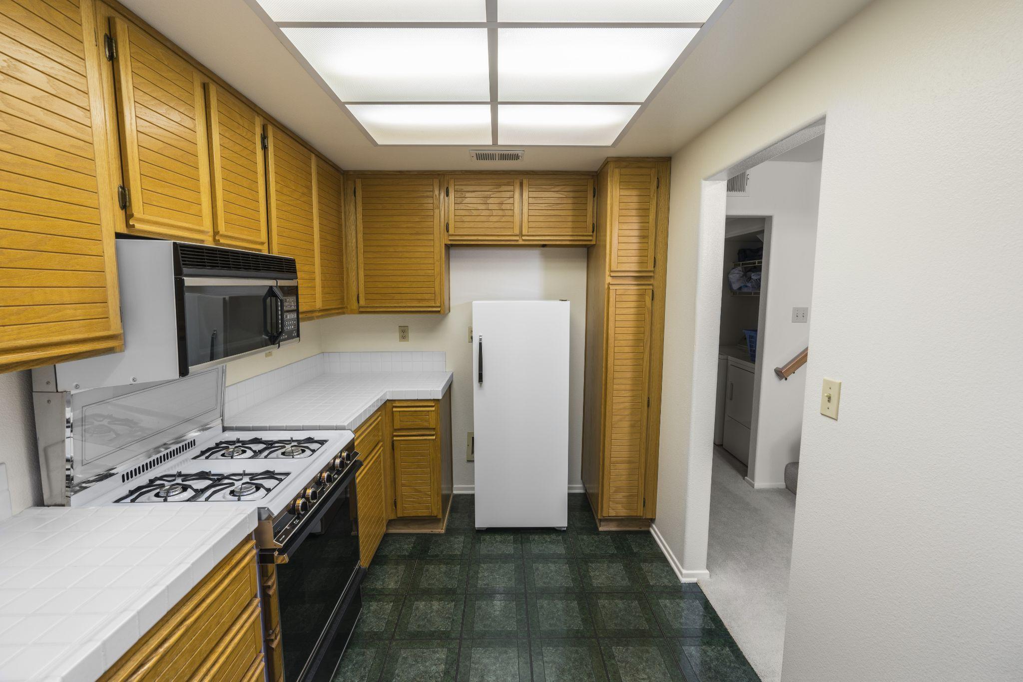 kitchen with oak cabinets, tile countertops, gas stove and green flooring