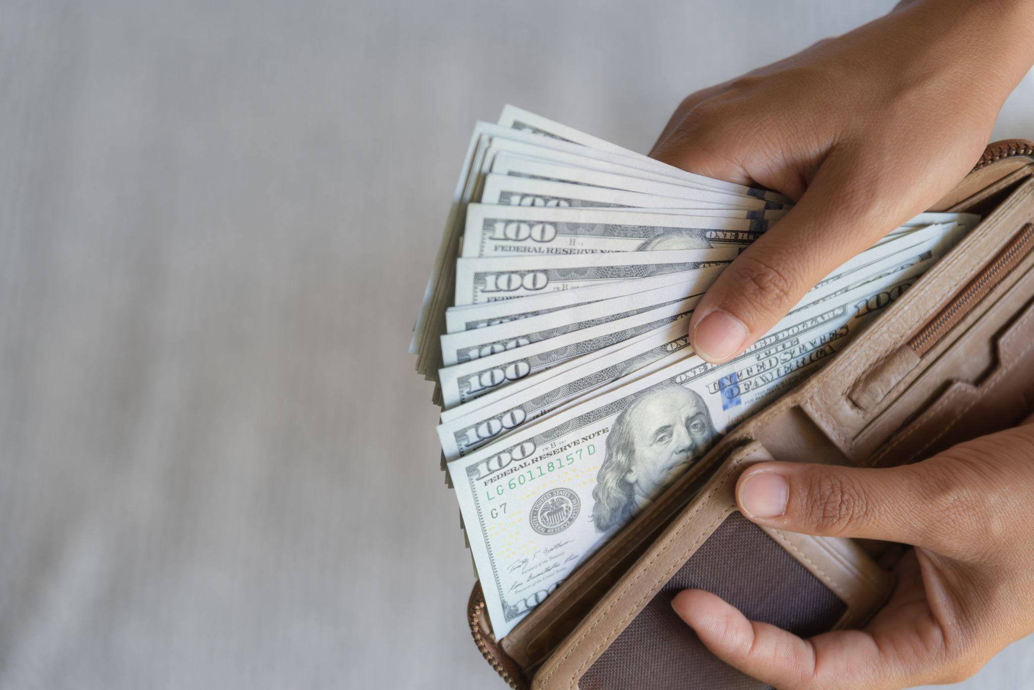 Man hands taking out money america dollars banknotes from wallet.