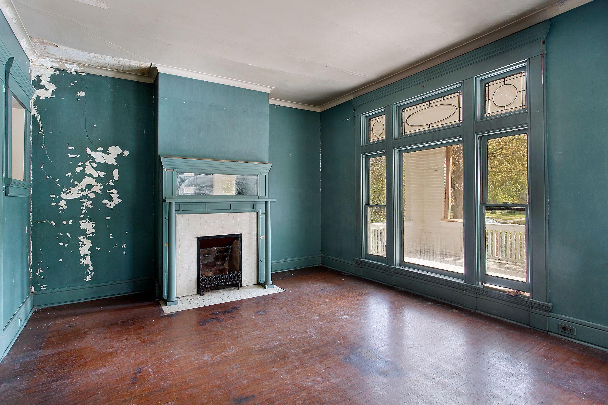 Old living room with peeling paint and scuffed flooring