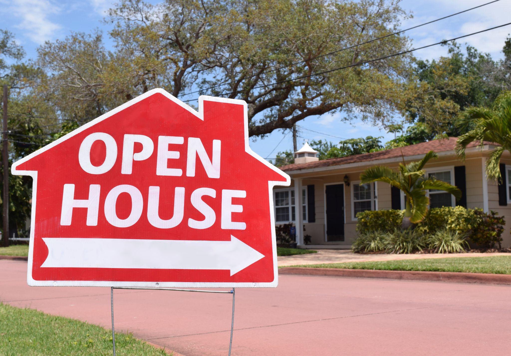 Open house real estate sign in yard, with house in background.