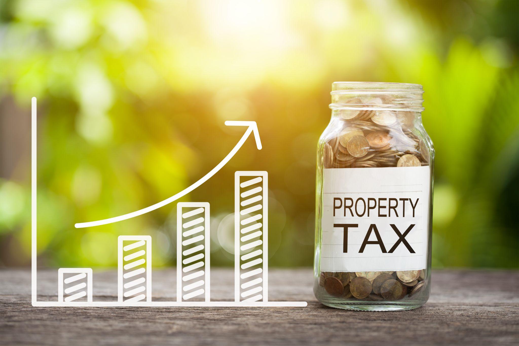 Property tax word with coin in glass jar and graph up