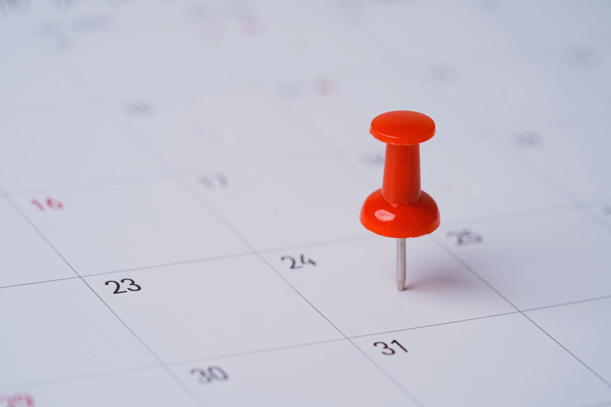 Red pin on calendar for business meeting and travel planing concept.