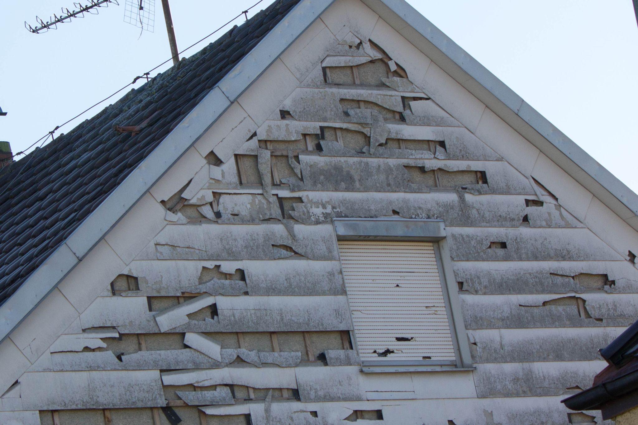 Storm damaged house with siding falling off