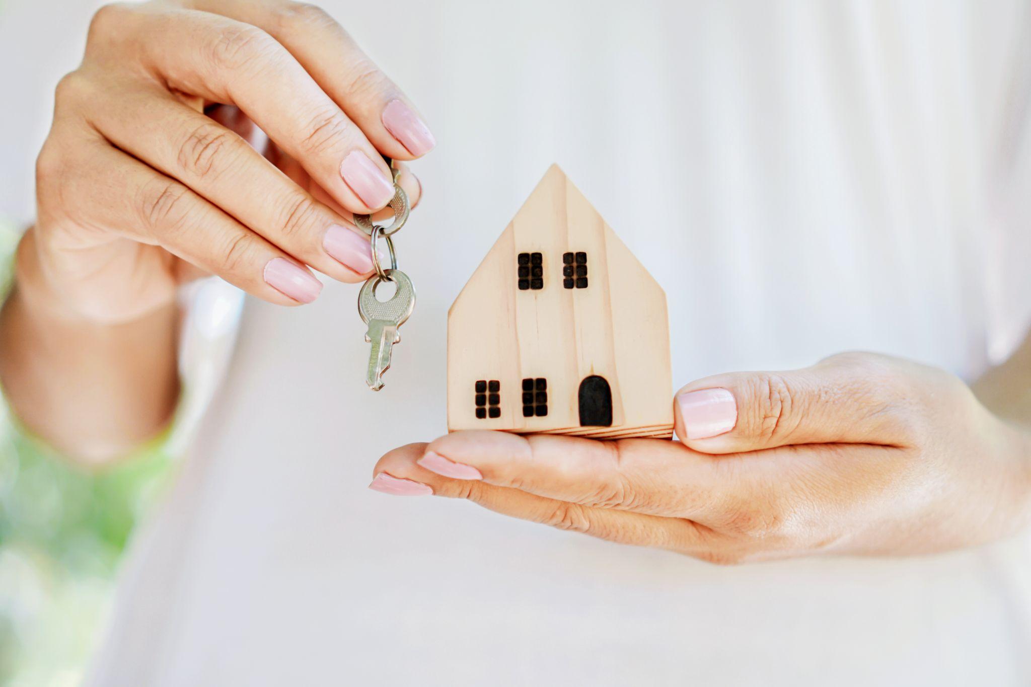 woman real estate agent hand holding key and house